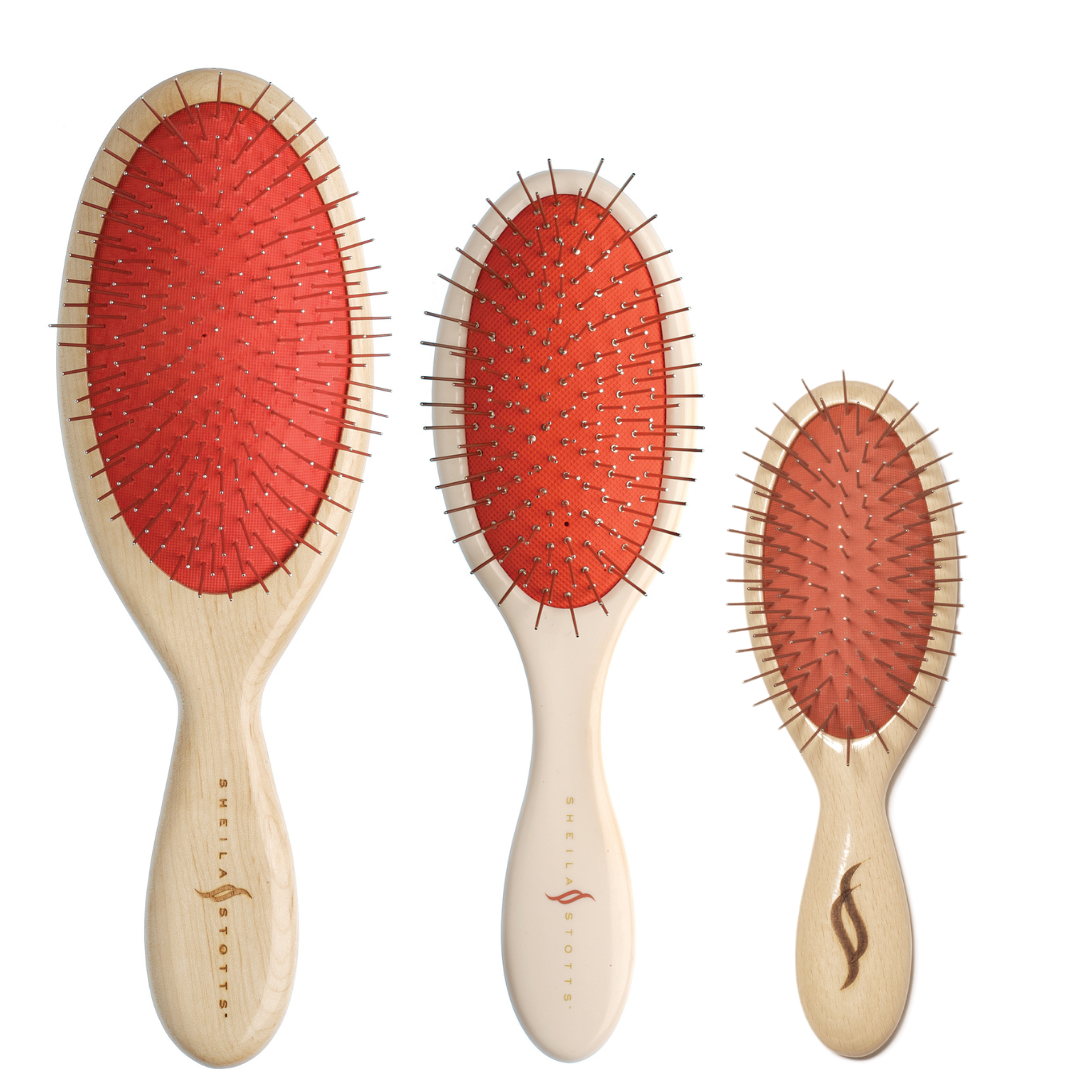Picture of all items included in gift set. 3 brushes varying in sizes. 1 Untangle wood large brush made of a solid maple wood handle, red/orange rubber pad and metal bristles. 1 Untangle brush made with a cream colored plastic handle, red/orange rubber pad, metal bristles featuring a drainage hole to be used in the shower or on wet hair. 1 Untangle Wood small brush made of a solid maple wood handle, red/orange rubber pad and metal bristles.