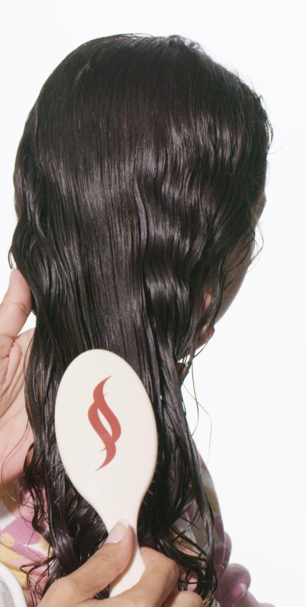 Wet long brown curly hair being effortlessly brushed with Untangle brush.